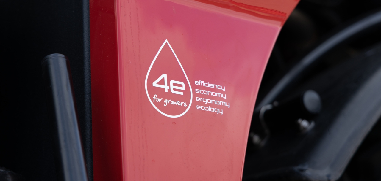 A close-up view of a red Agrifac sprayer featuring a prominent sticker on its body, showcasing a slogan.
