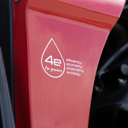 A close-up view of a red Agrifac sprayer featuring a prominent sticker on its body, showcasing a slogan.