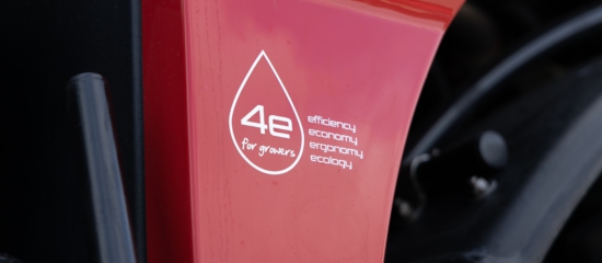 A close-up view of a red Agrifac sprayer featuring a prominent sticker on its body, showcasing a slogan.