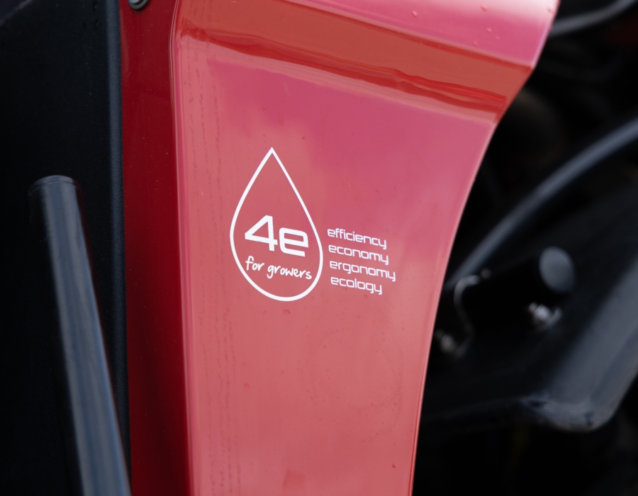 A close-up view of a red Agrifac sprayer featuring a prominent sticker on its body, showcasing a slogan.