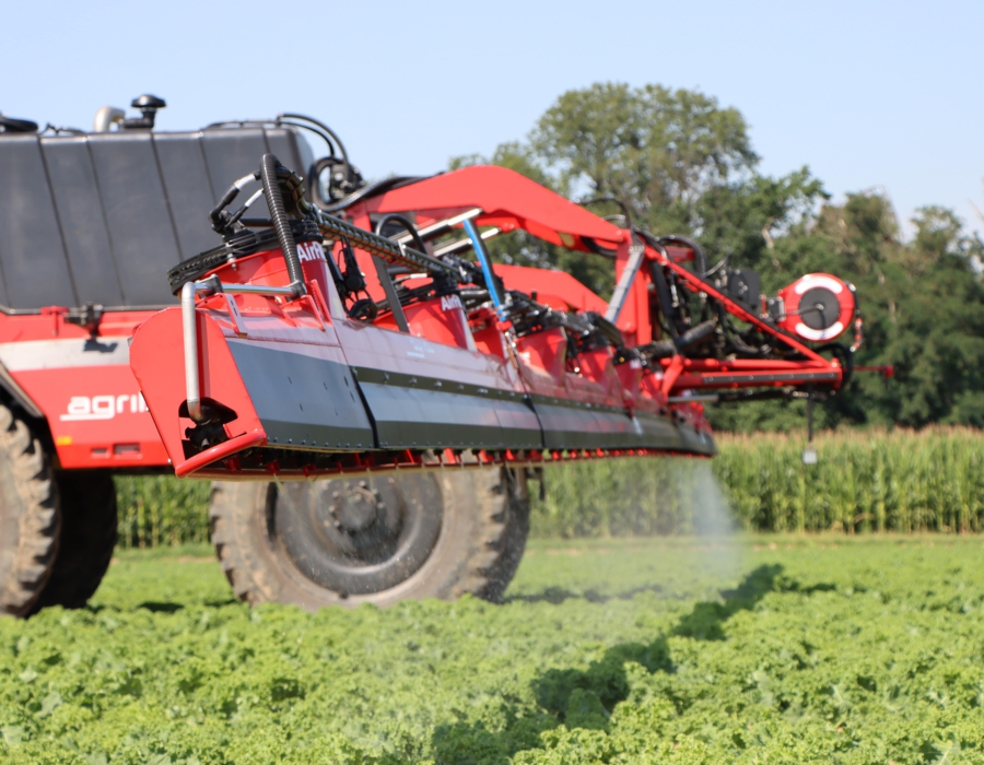 An Agrifac sprayer applying liquid to a field, showcasing agricultural practices in a vibrant landscape.
