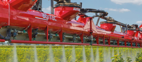 An Agrifac sprayer with AirFlow boom, spraying a green field, showcasing agricultural action and drift reduction.