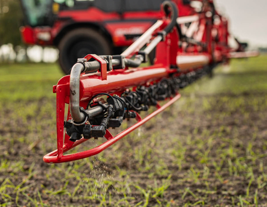 An Agrifac sprayer applying liquid to a lush green grass field, showcasing agricultural practices in a vibrant landscape.