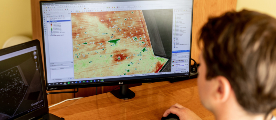 A man sits at a desk, focused on a computer screen displaying a detailed task map for navigation or planning purposes.