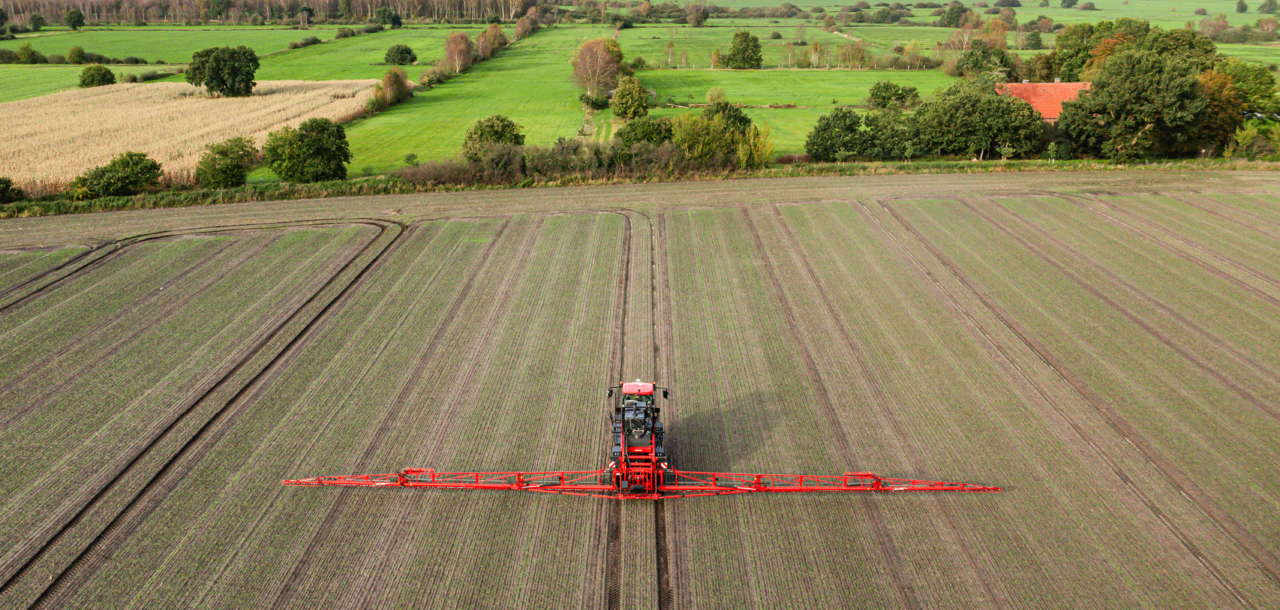 Aerial view of an Agrifac sprayer driving in a vast agricultural field, showcasing modern farming techniques.