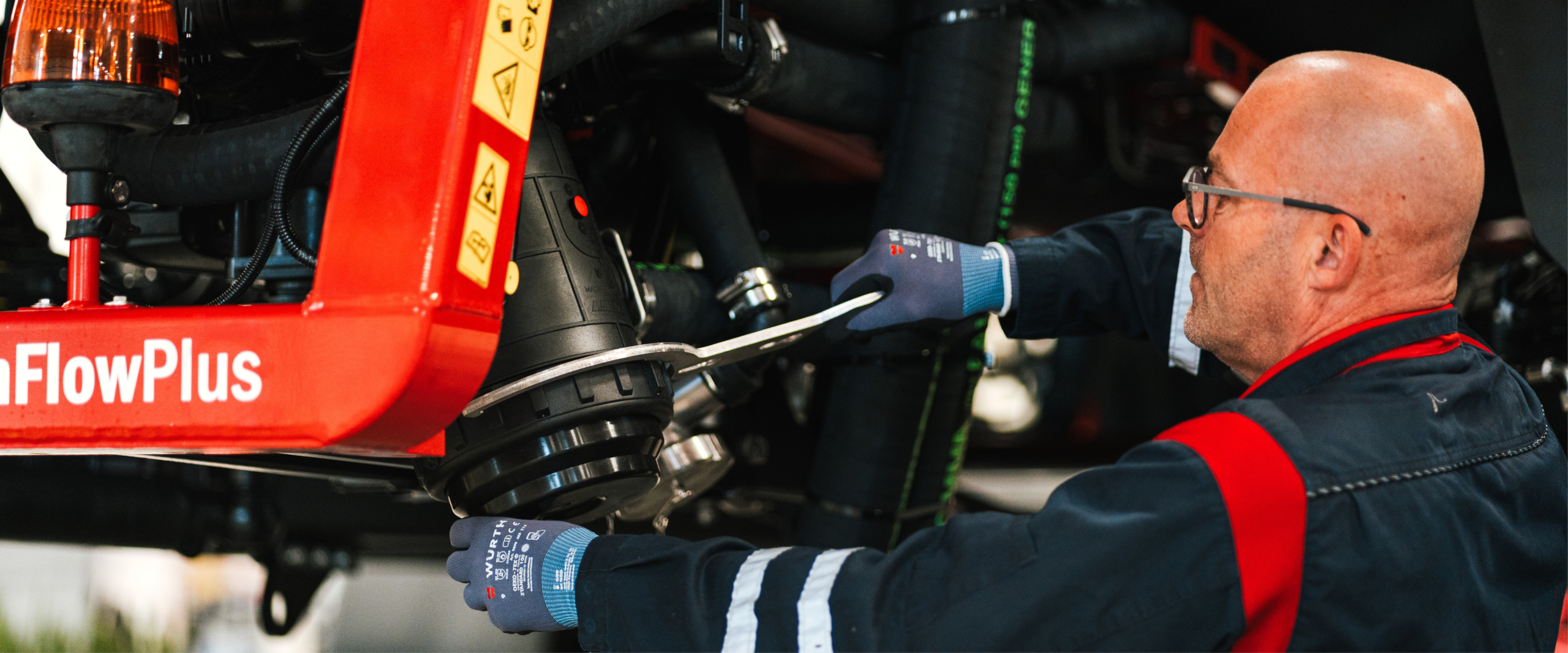 A person, dressed in work clothes, is assembling an agricultural machine.