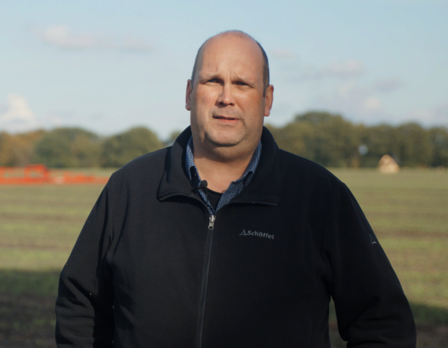 A bald man standing in an agricultural field.