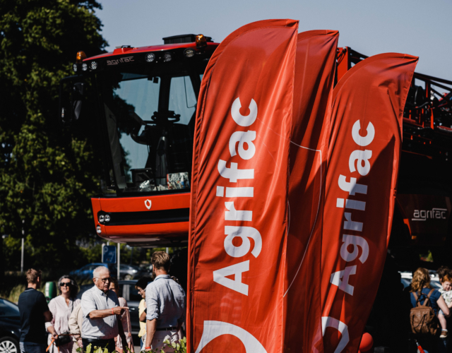 Two flags and part of a machine visible at an outdoor event.
