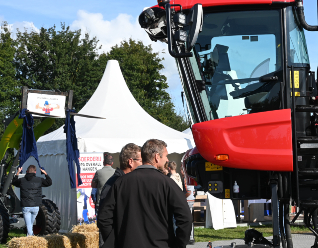Two people standing next to a machine at an outdoor exhibition.