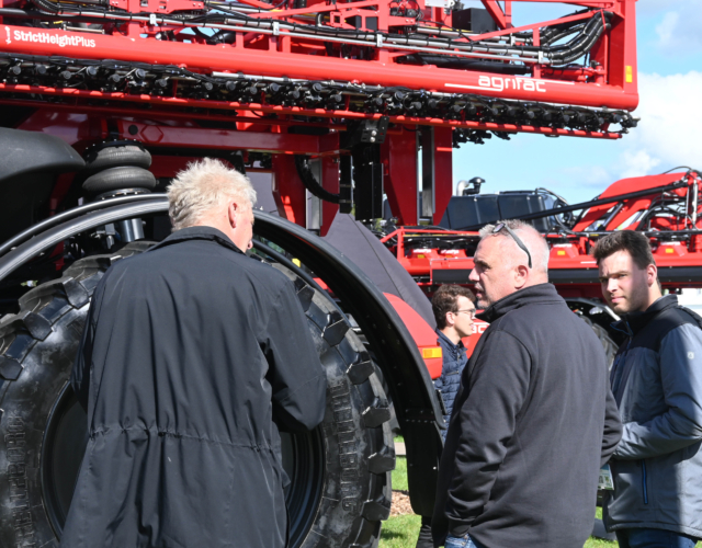 Three people in conversation in front of a sprayer.