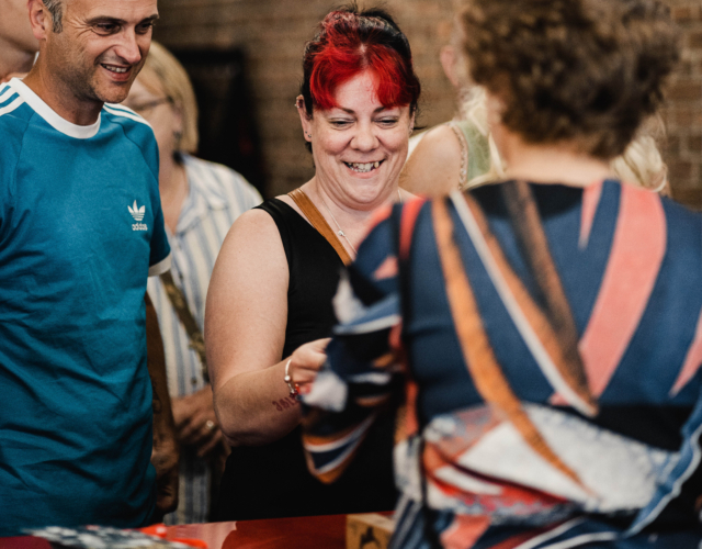 Person smiling while being presented with an item.