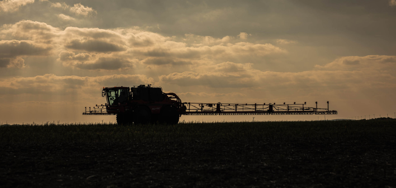 Silhouette of a AiCPlus sprayer in a field.