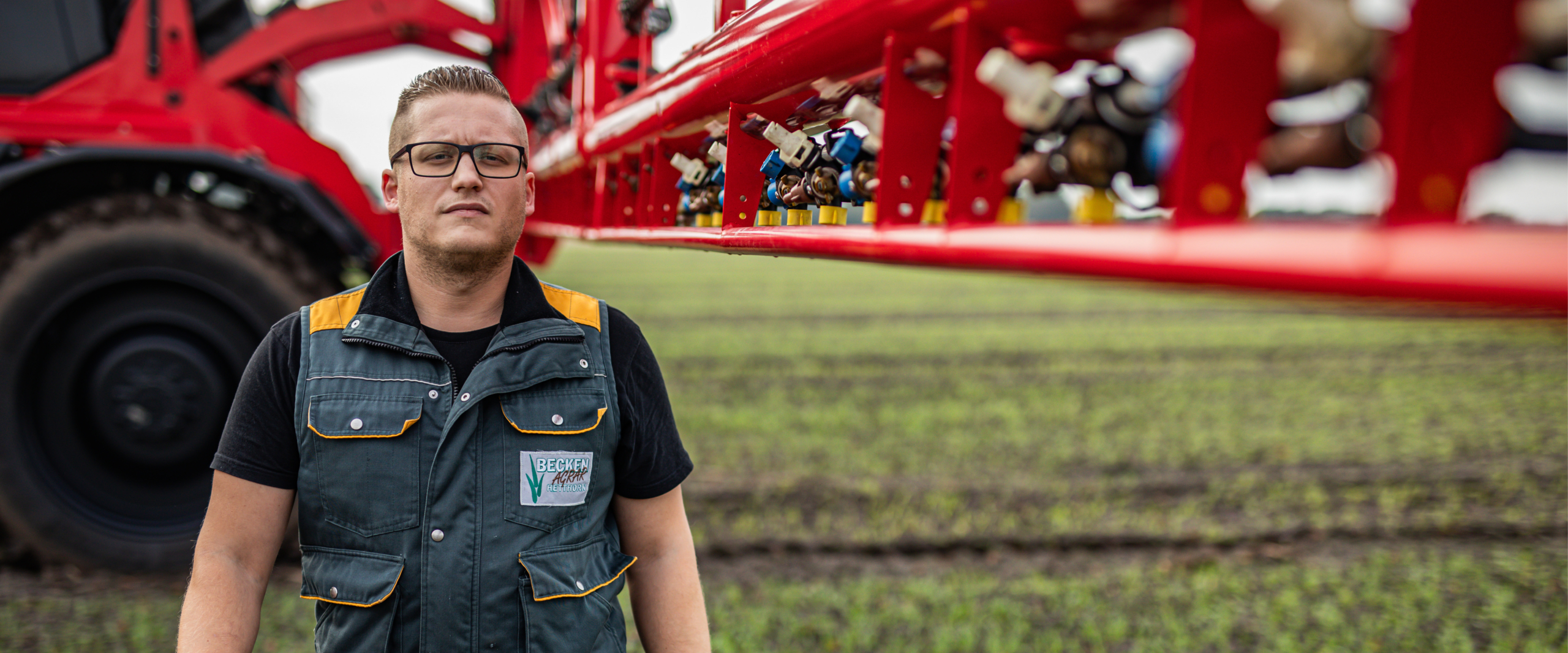 A man standing right in front of an Agrifac sprayer.