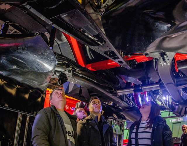 People inspecting the underside of a machine.