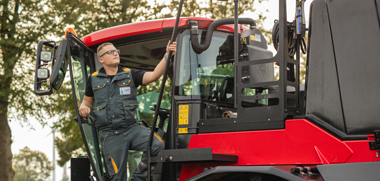 A man standing on the platform of an Agrifac Condor sprayer, checking it's equipement.