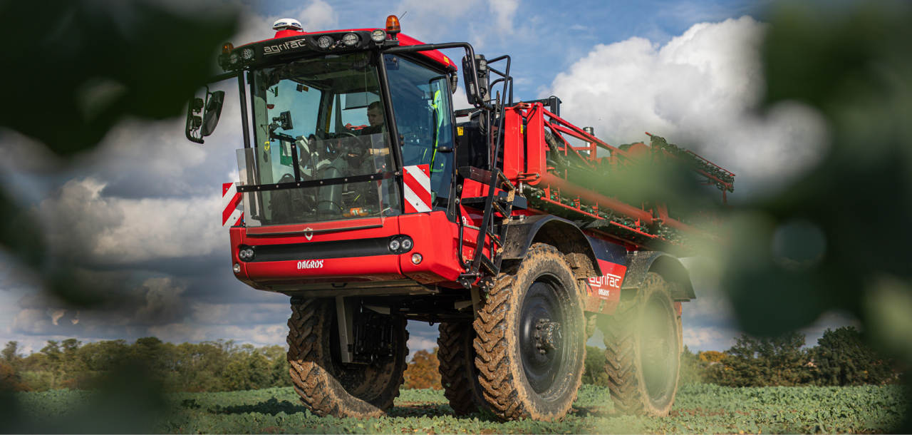 An Agrifac sprayer peaking through the leaves of a tree.