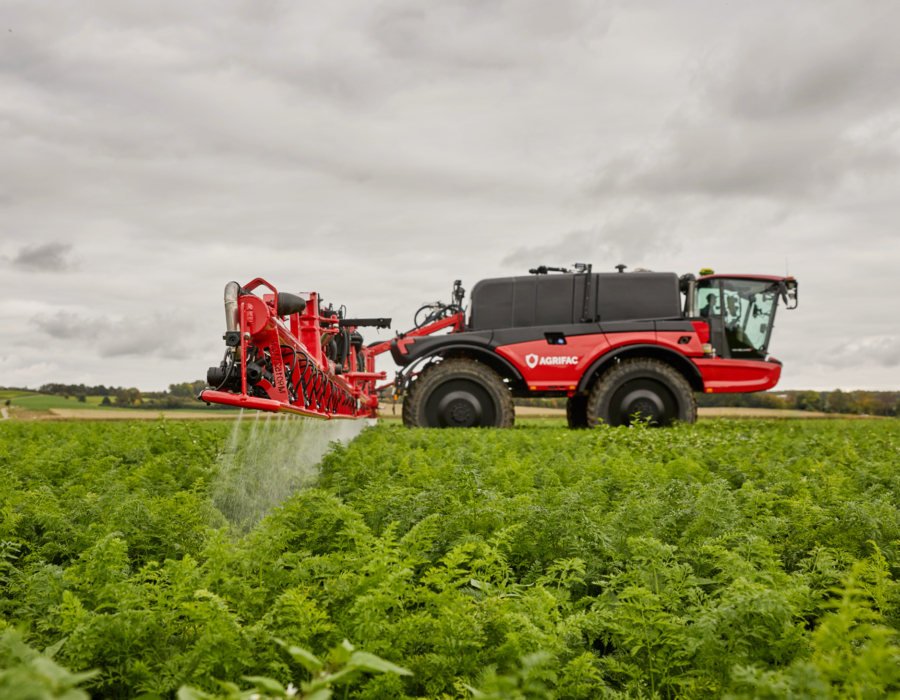 Side view of the machine with the J-boom spraying crops.