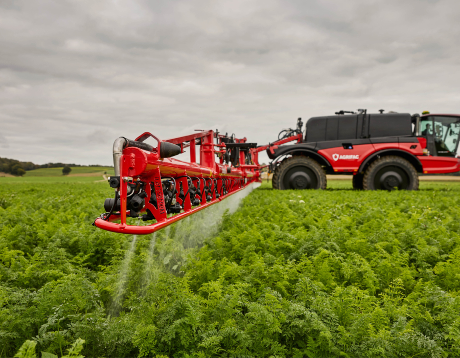 Side view of the machine with the J-boom spraying crops.